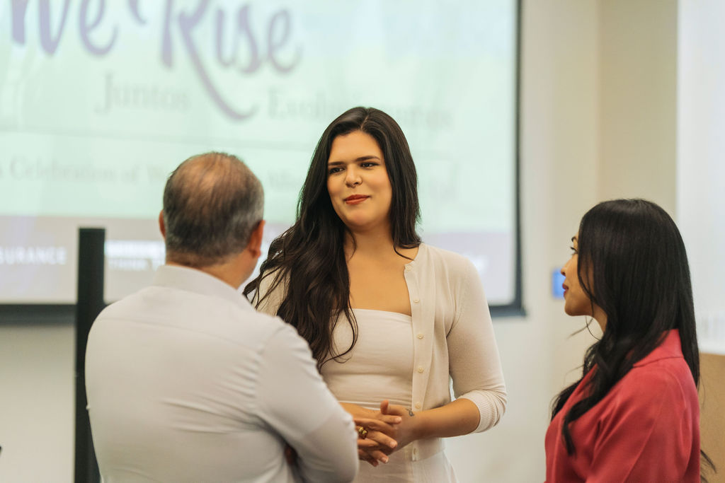 Guests chatting in front of the WE RISE 2025 stage screen