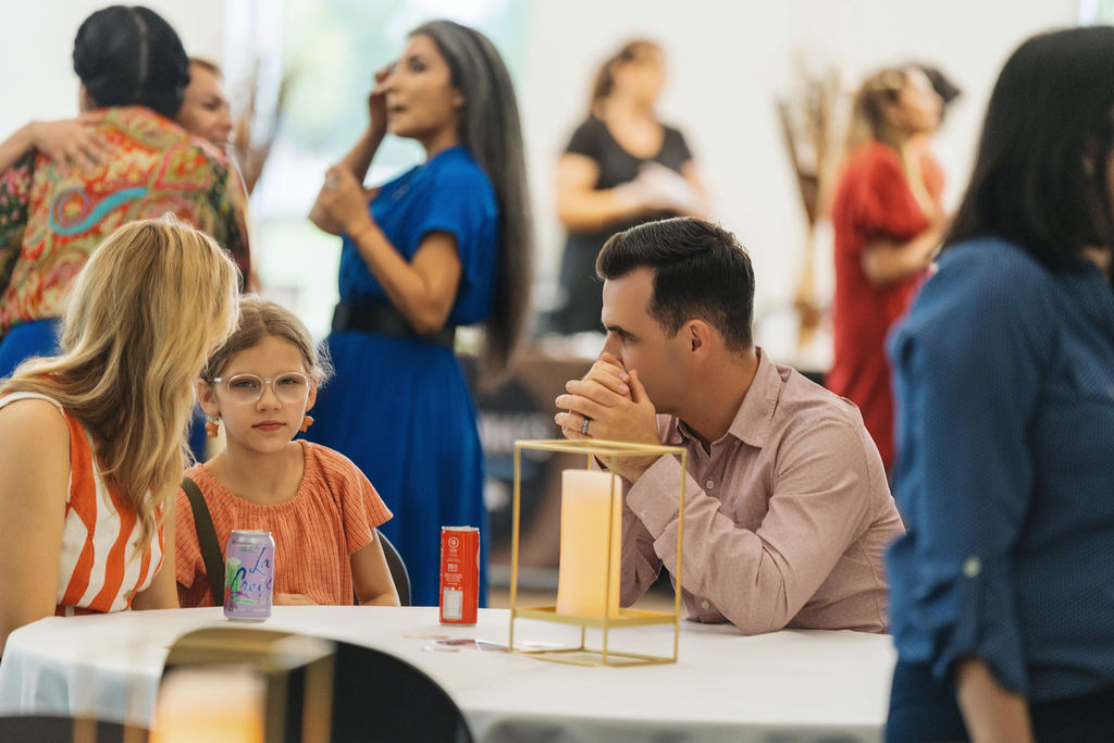 Guests visiting around a candlelit table at WE RISE 2025
