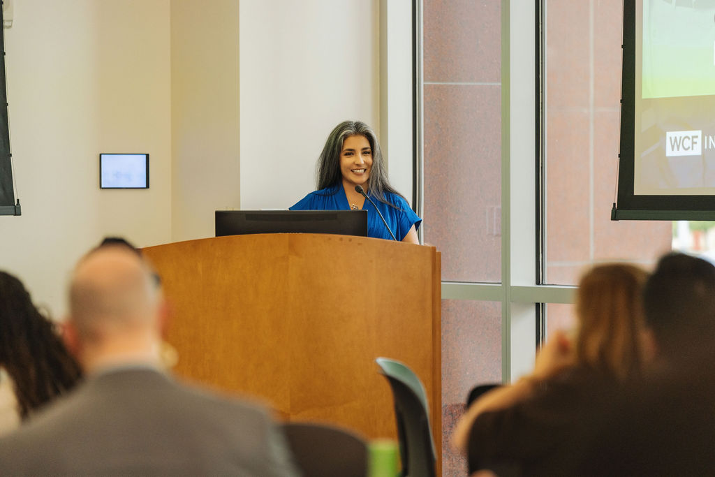 Host welcoming guests from the podium at WE RISE 2025